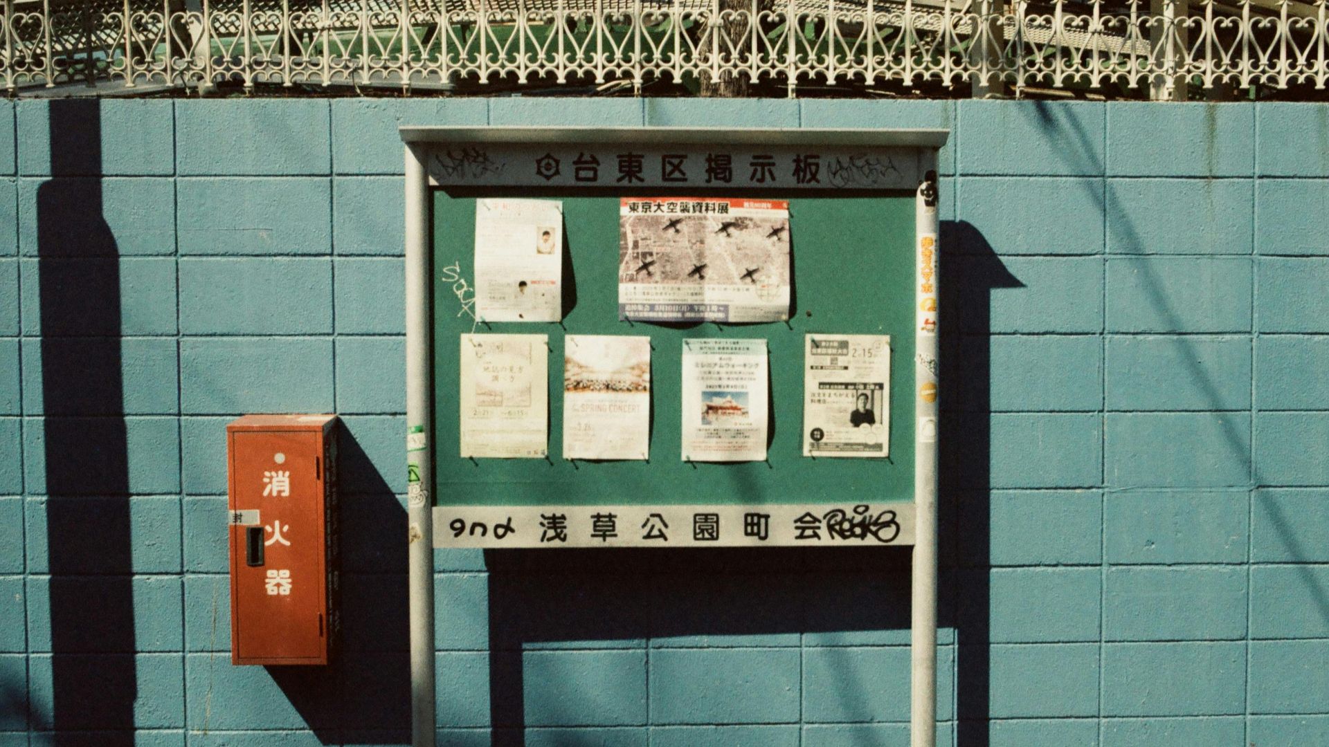 A vintage notice board with posted papers against a blue brick wall in Tokyo, Japan.