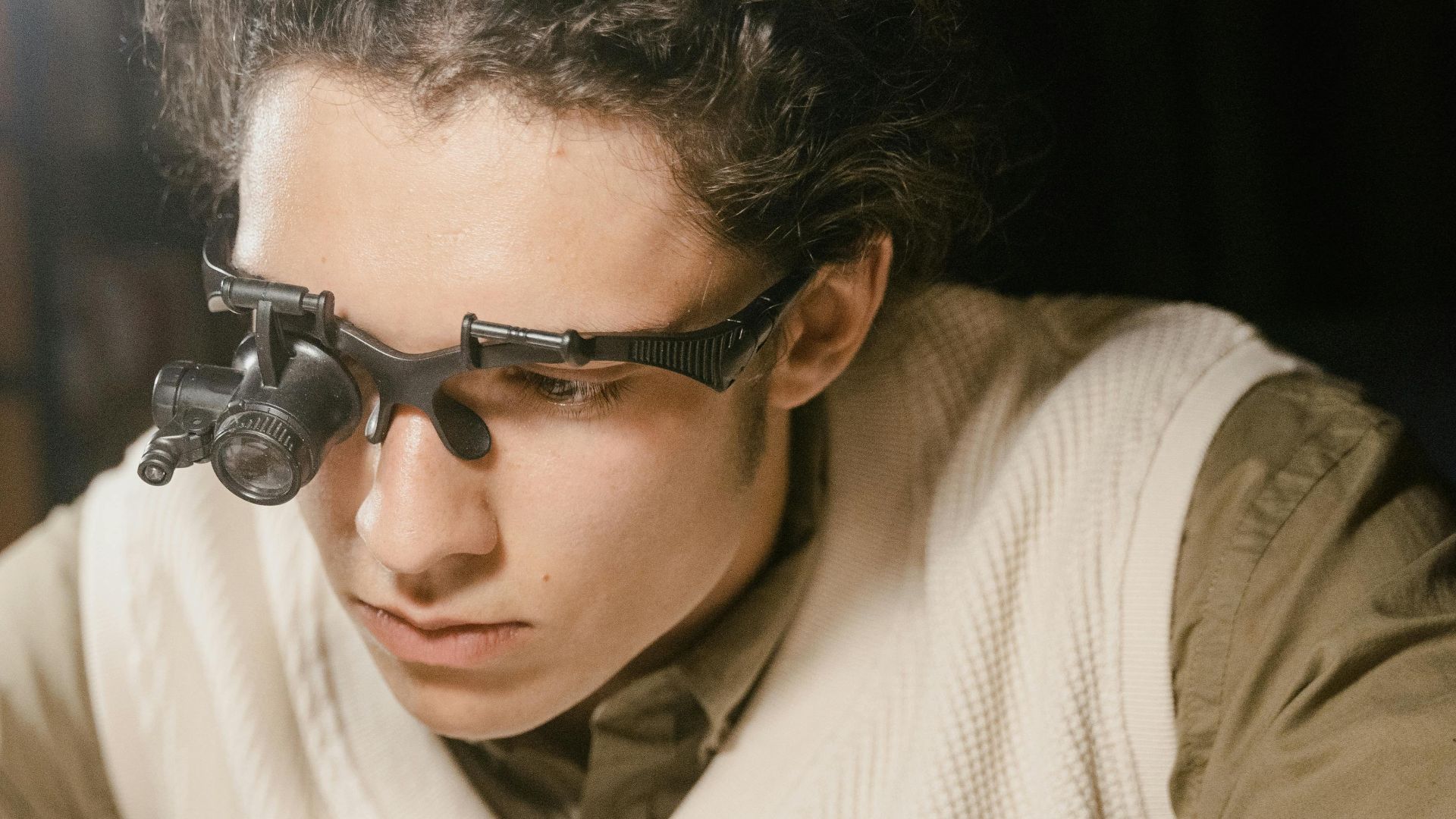 A watchmaker uses a headband magnifier for precise timepiece repair.