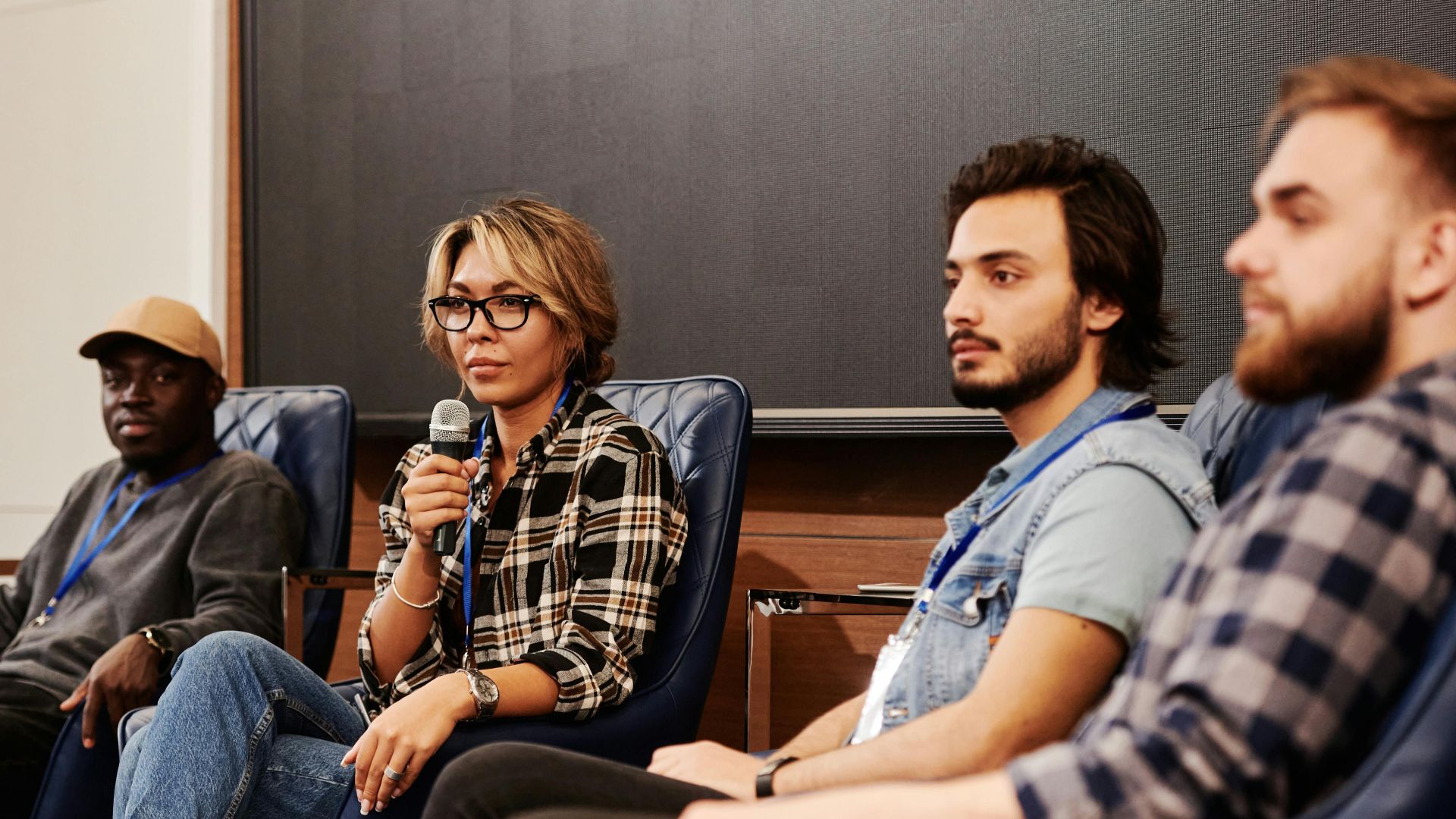 A diverse group of individuals engaged in an informative panel discussion at an indoor event.