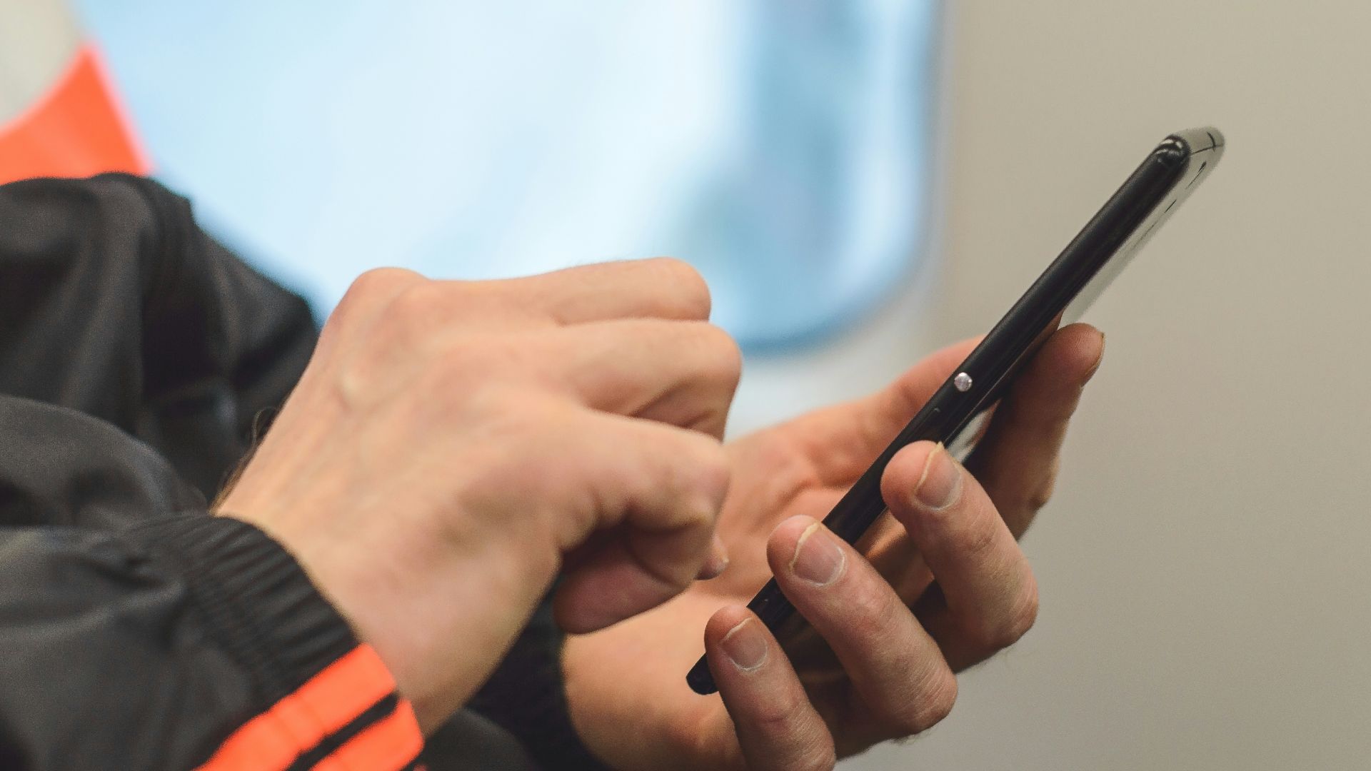 person in black and orange long sleeve shirt holding black pen