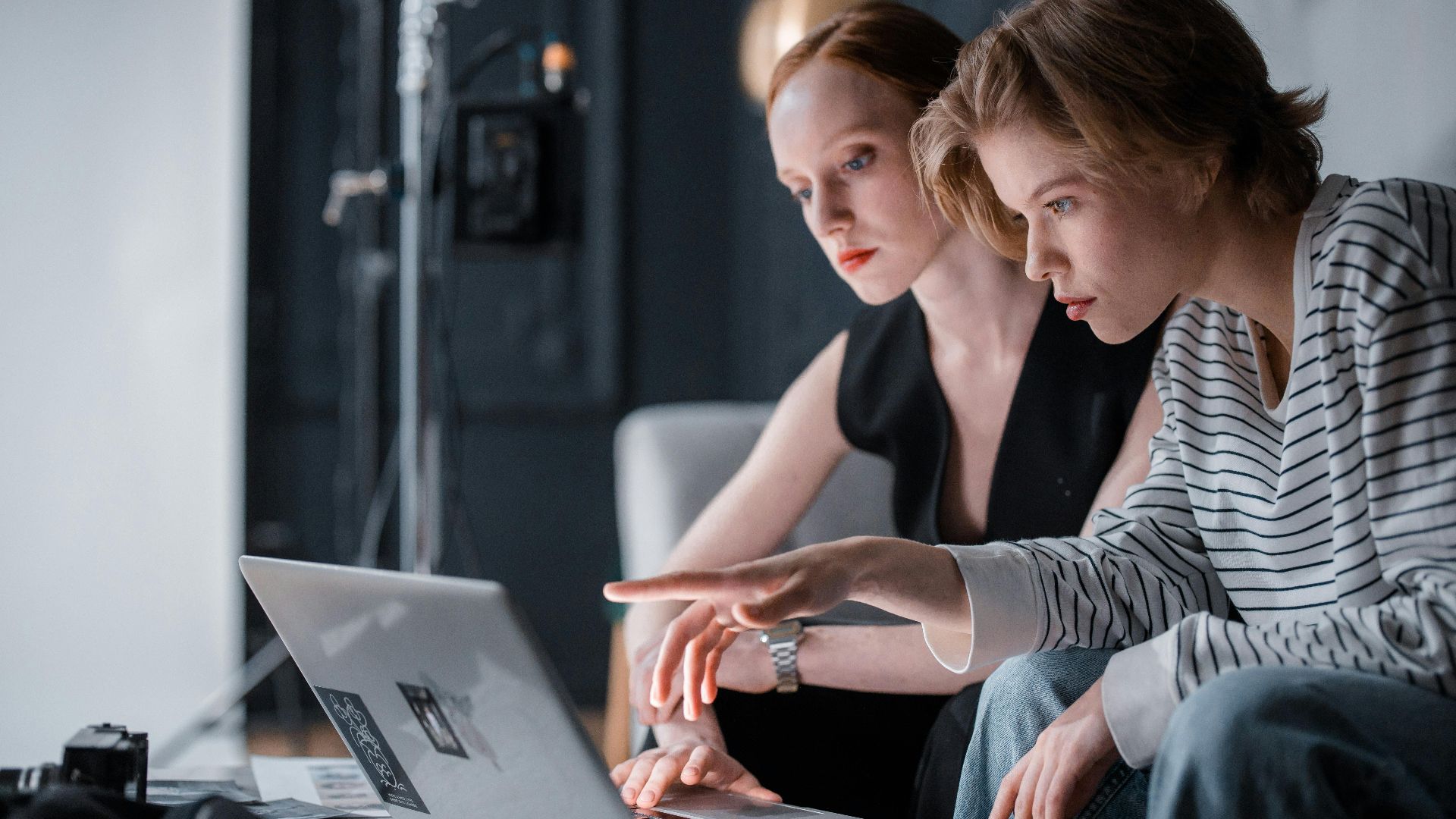 Two focused individuals collaborating on a laptop in a professional indoor setting.