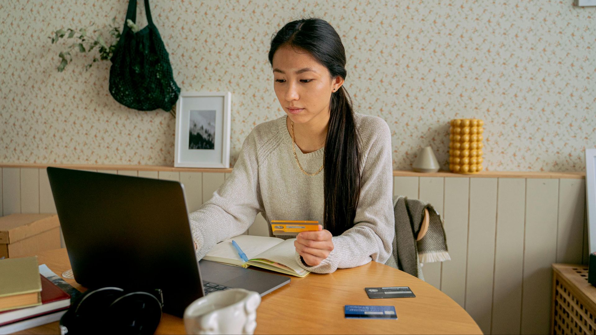 A woman using a laptop and credit card for online shopping at a cozy indoor setting.
