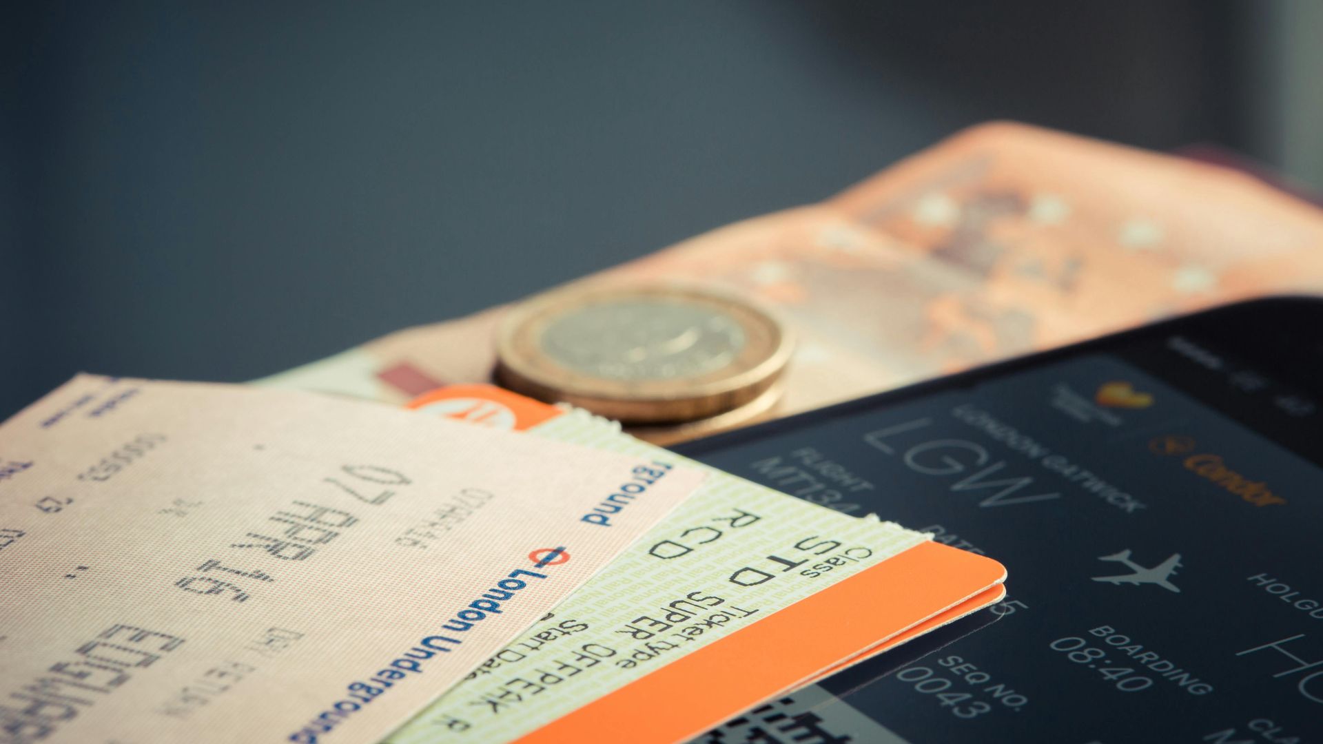 Airline ticket with euro coins and smartphone displaying flight details.