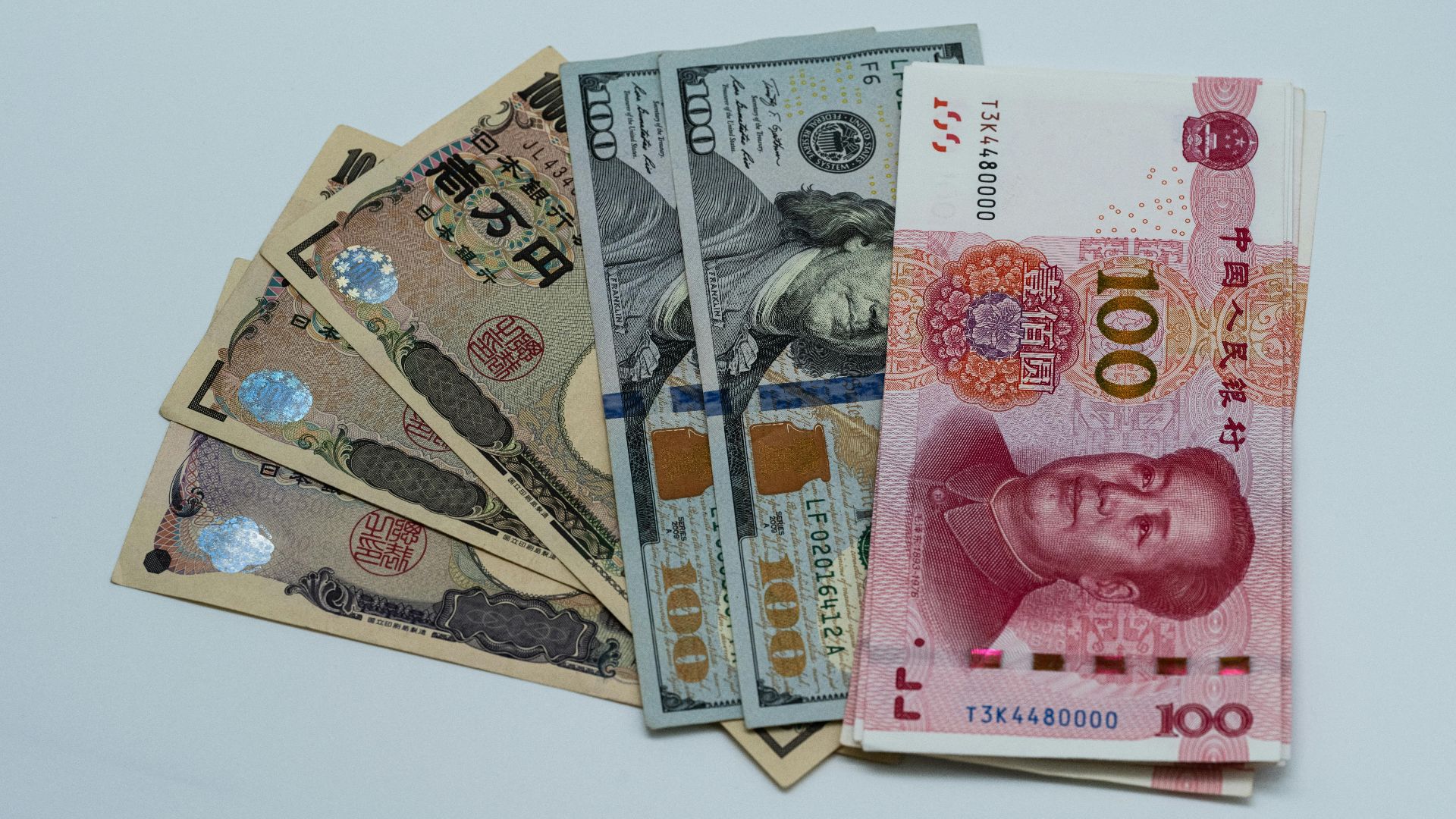 Various international currency notes including US dollars, yen, and yuan arranged on a surface.