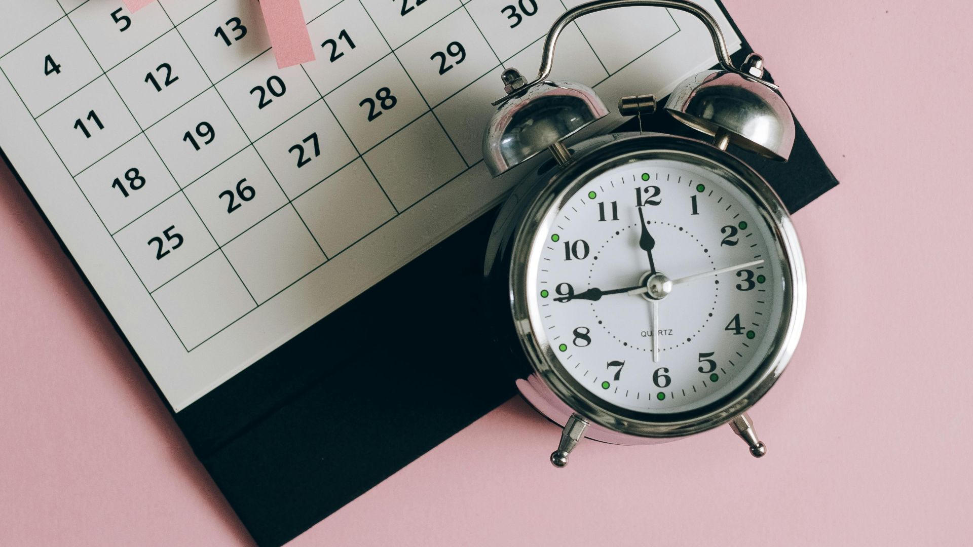 Calendar with pink ribbon, an alarm clock, and the text