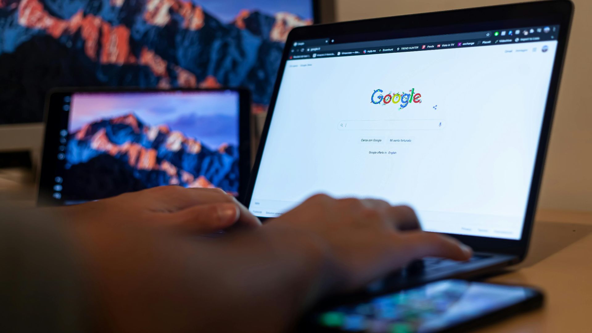 Hands typing on a laptop with Google on screen, in a remote work setup in Milan, Italy.
