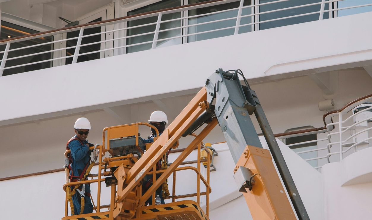 Man Working on Scissor Lift by Passenger Ship