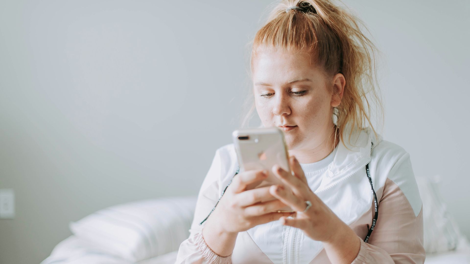woman sitting on bed while using gold turned 8 Plus