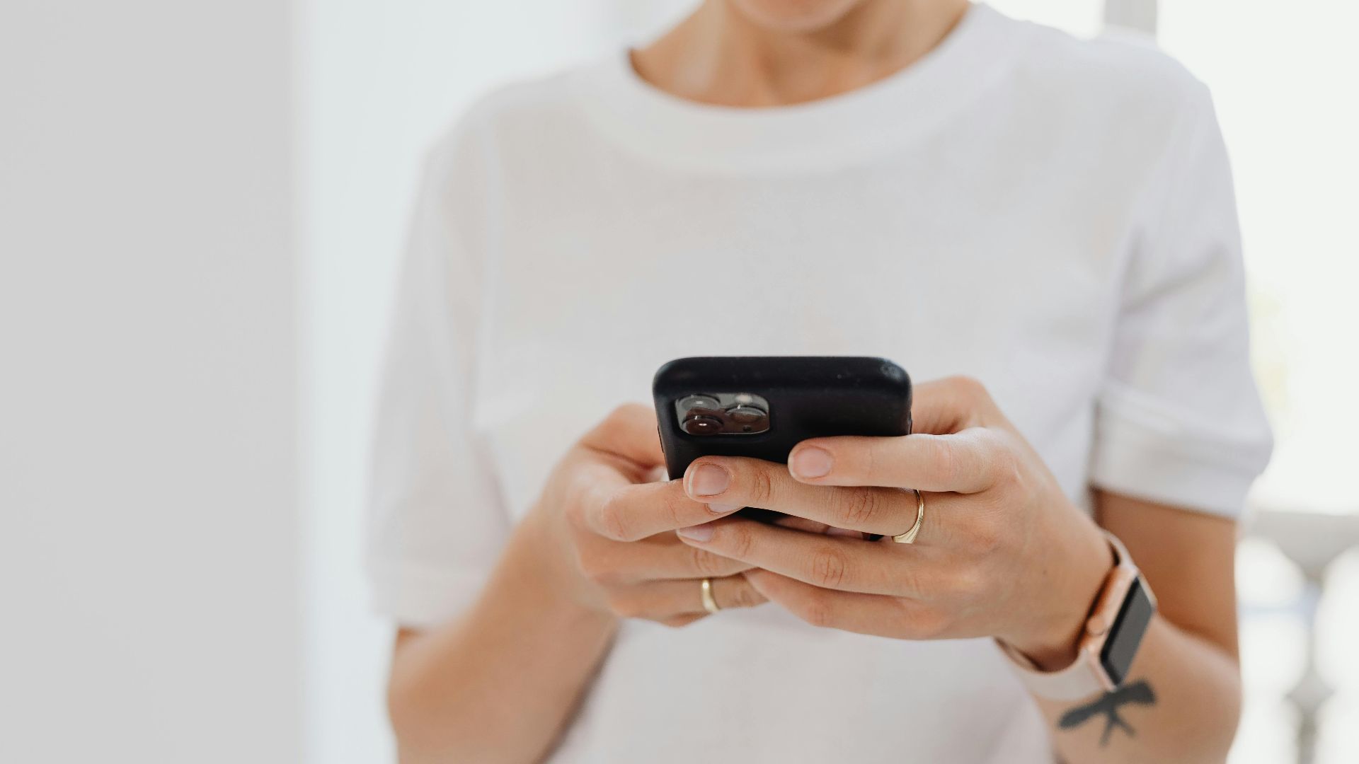 Adult using smartphone indoors, focusing on touchscreen communication.