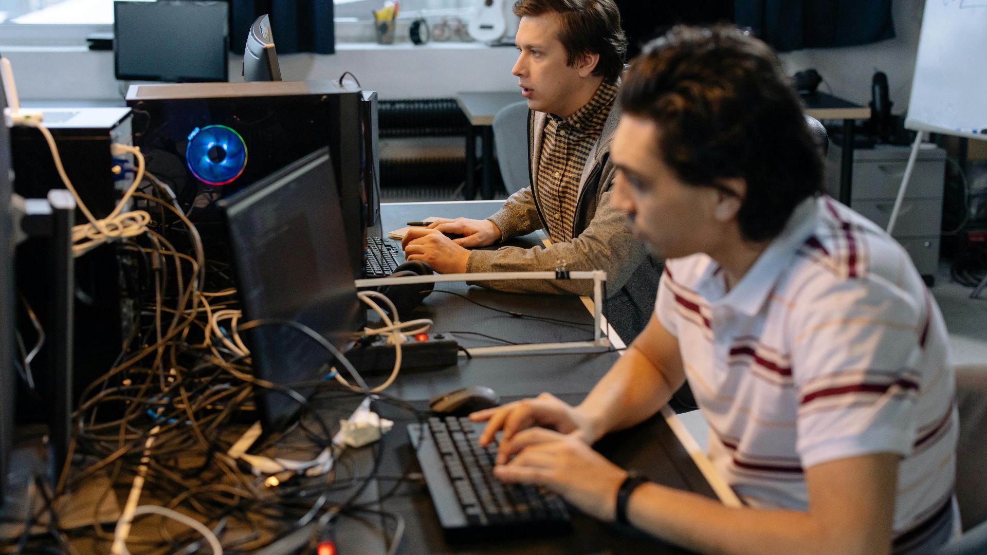 Male programmers working on computers in a modern office setting, showcasing teamwork and technology.
