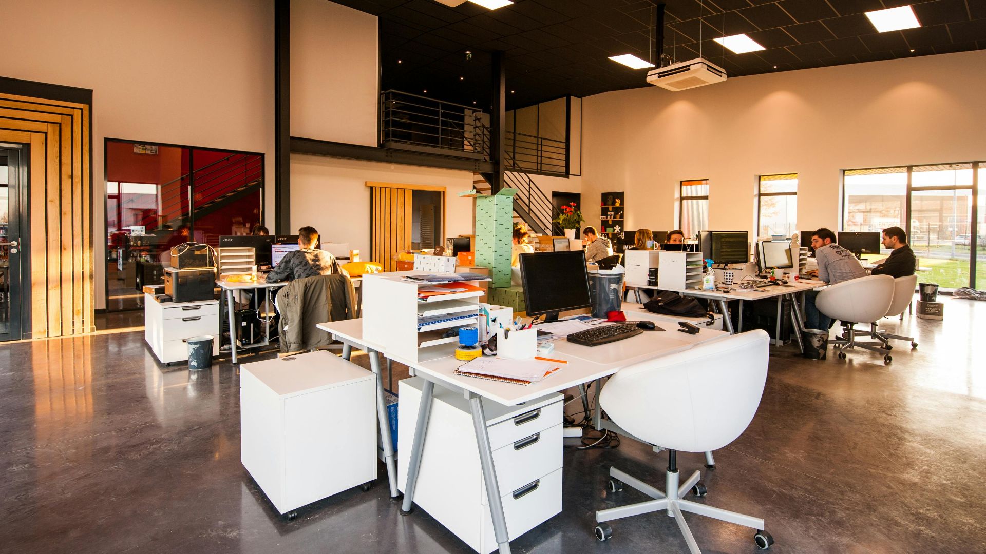 A spacious and modern open-plan office with natural lighting and employees working at desks.