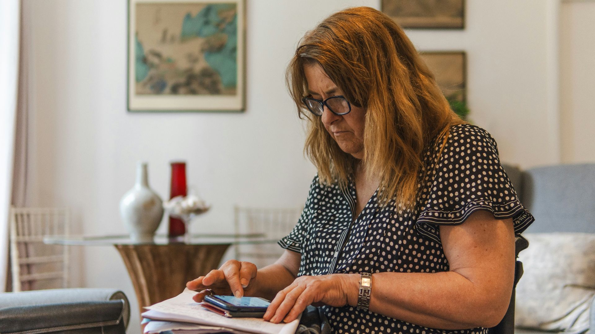 Woman looking at phone while writing on paper
