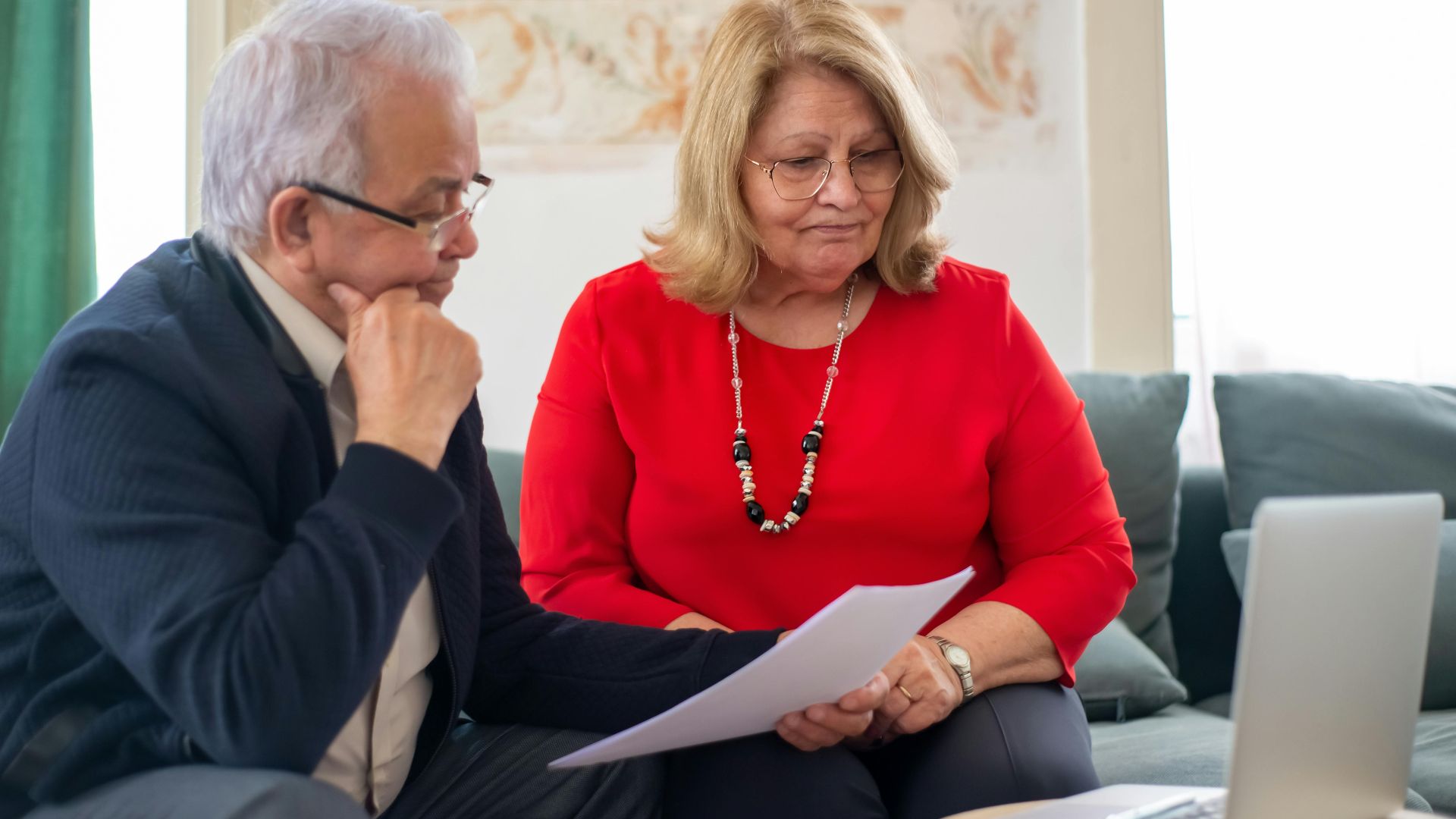 Elderly couple reviewing financial documents together at home in Portugal.