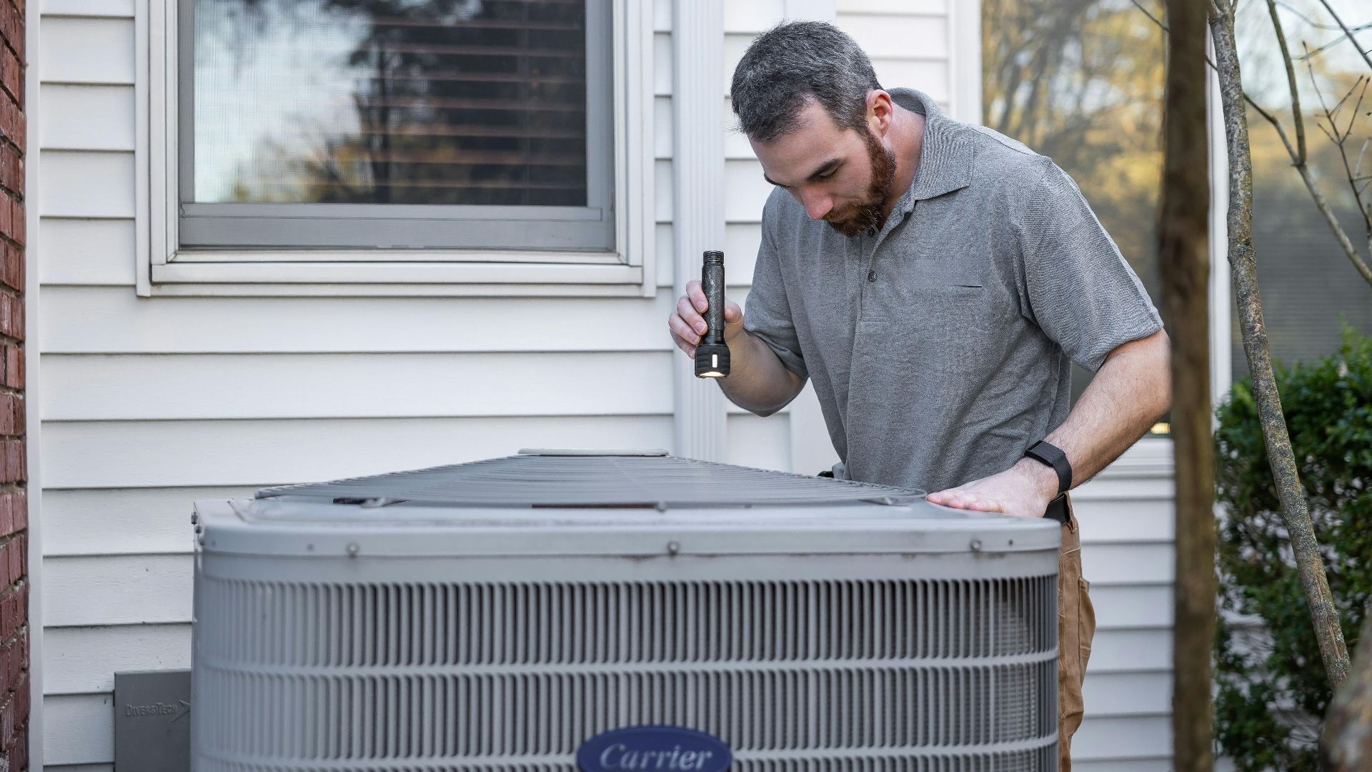 A technician inspects an outdoor HVAC unit for maintenance.