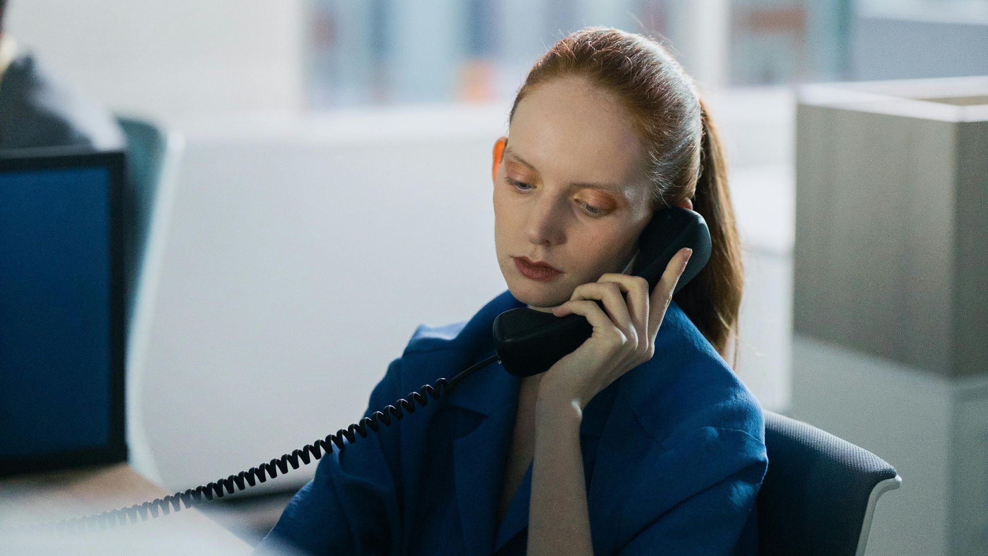 Focused businesswoman talking on phone in modern open office environment.