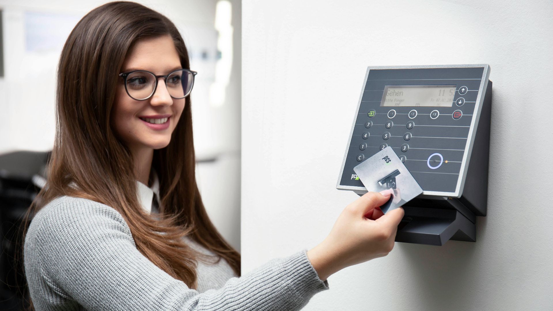 Smiling woman uses a card reader for secure office access in Munich.