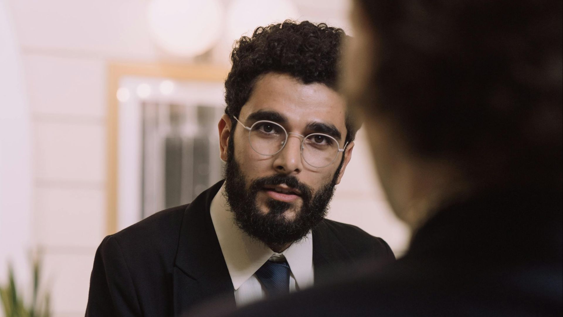 A professional businessman checks in at a hotel reception, engaging with a concierge.
