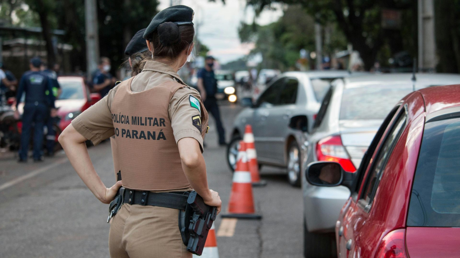 Back view of a police officer in uniform controlling traffic on a busy road.