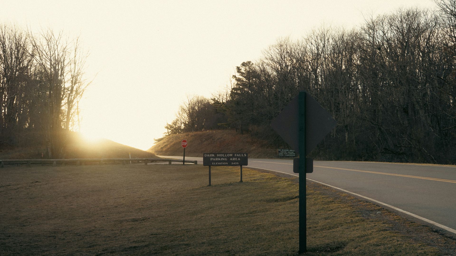Sunset over a grassy area with trees and road.