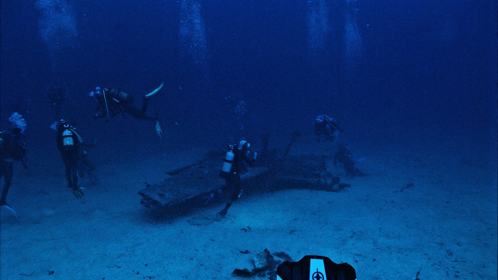 Divers exploring underwater wreckage during a deep ocean scuba dive.