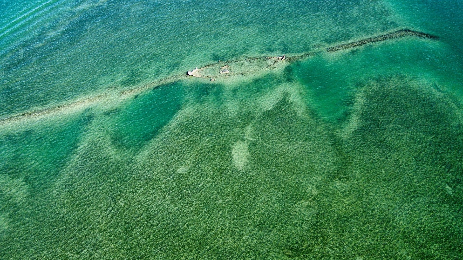 Shipwreck visible beneath clear turquoise ocean water.
