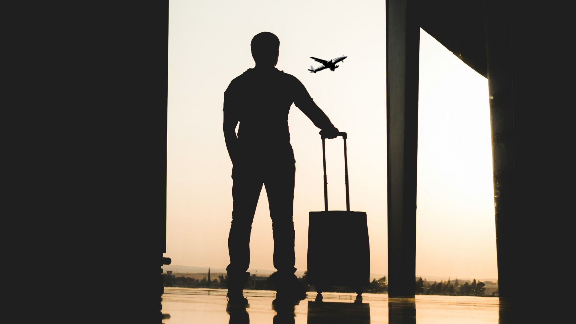 silhouette of man holding luggage inside airport