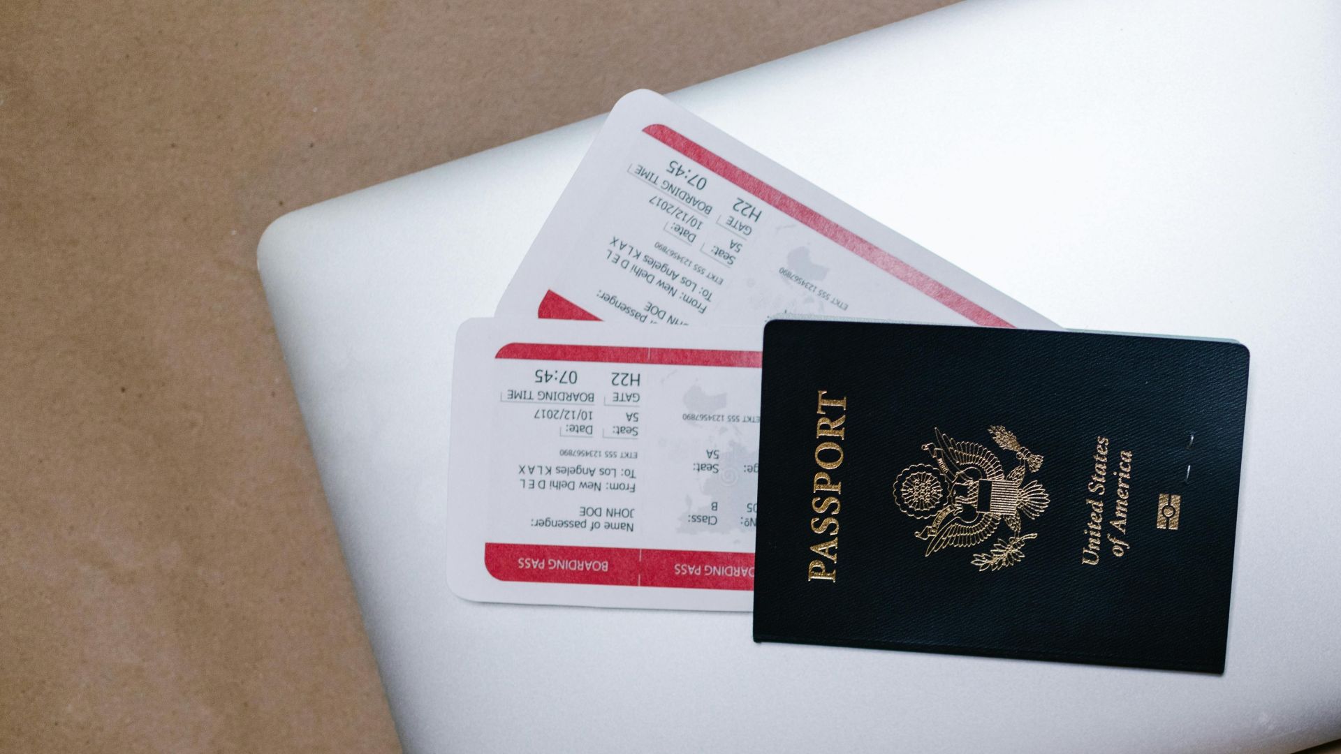 Close-up of a passport and boarding passes on a laptop, symbolizing travel preparation.