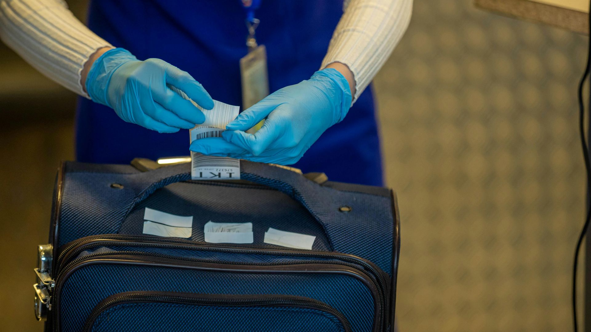 Close-up of airport security process with gloved hands inspecting luggage tags.