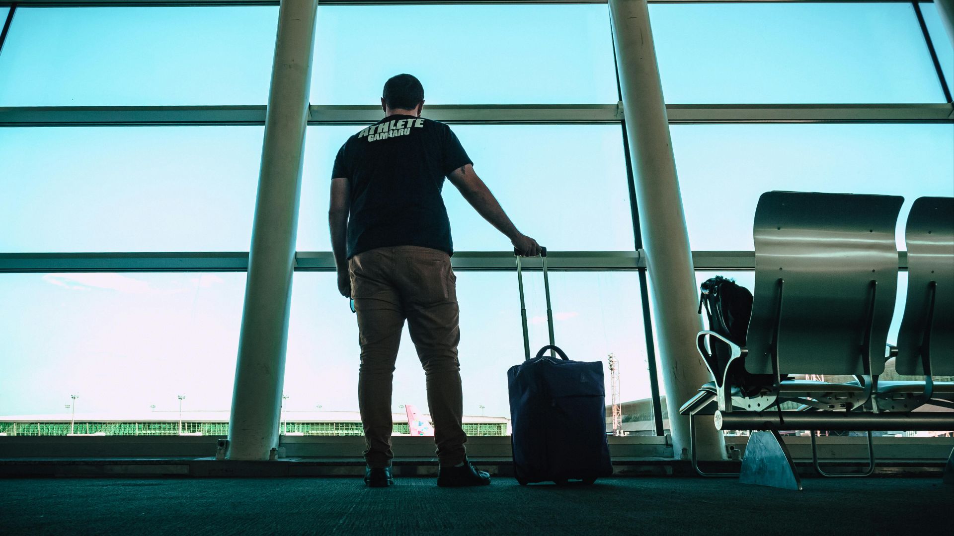 Man with luggage waiting at airport lounge, anticipating departure in a modern setting.