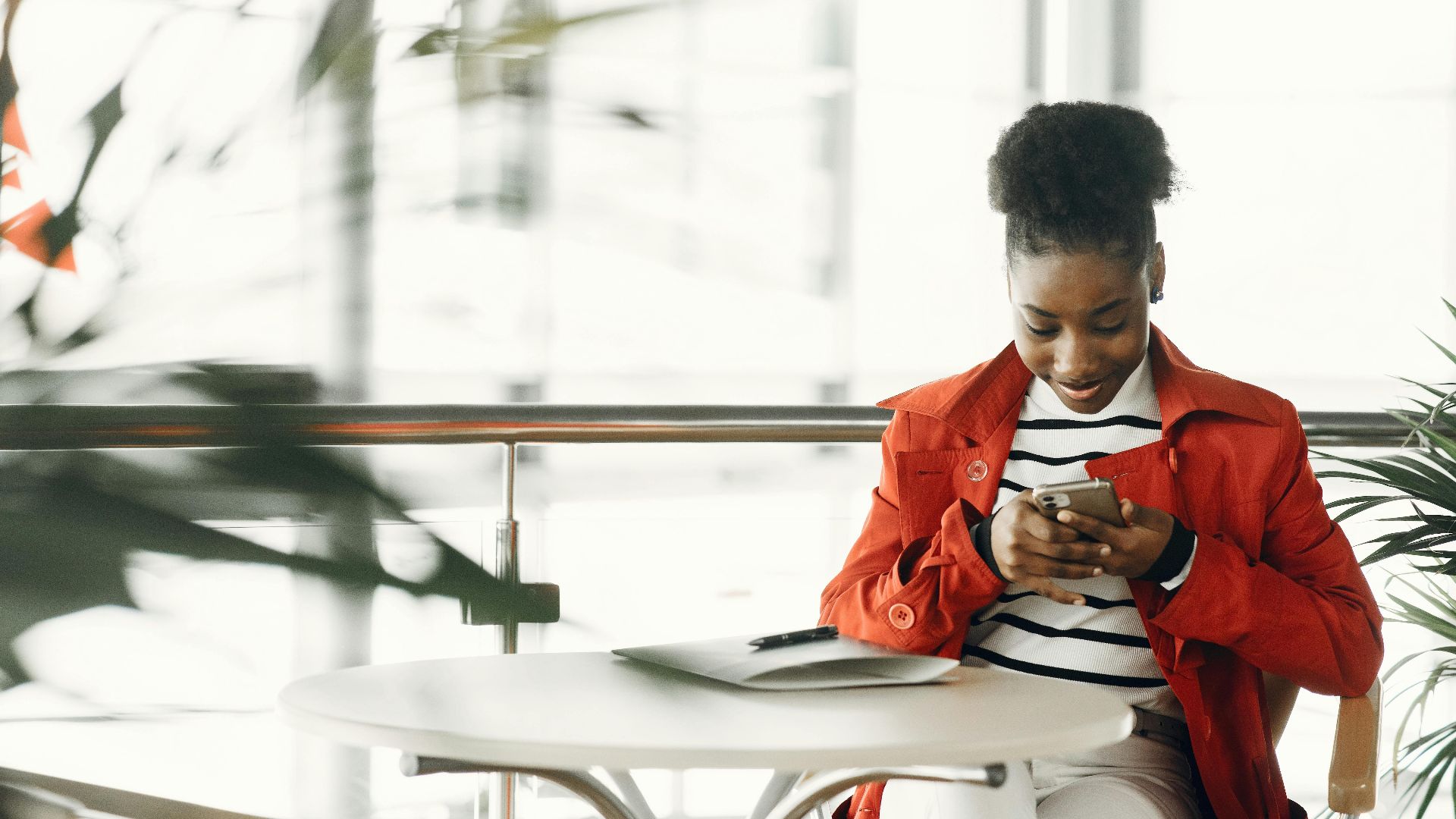 African American woman sitting and using smartphone in cozy café environment.