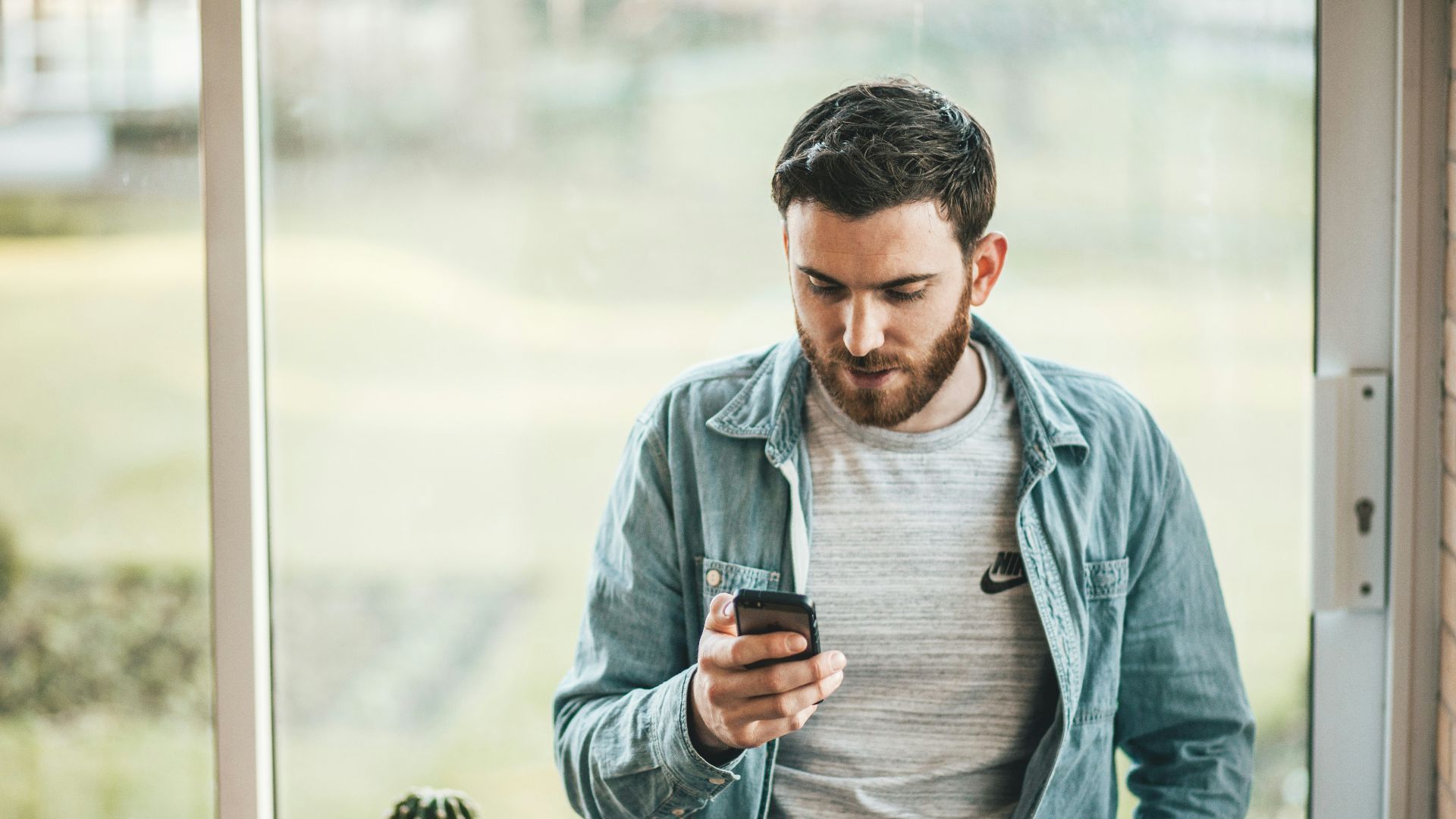 man holding a smartphone near the window