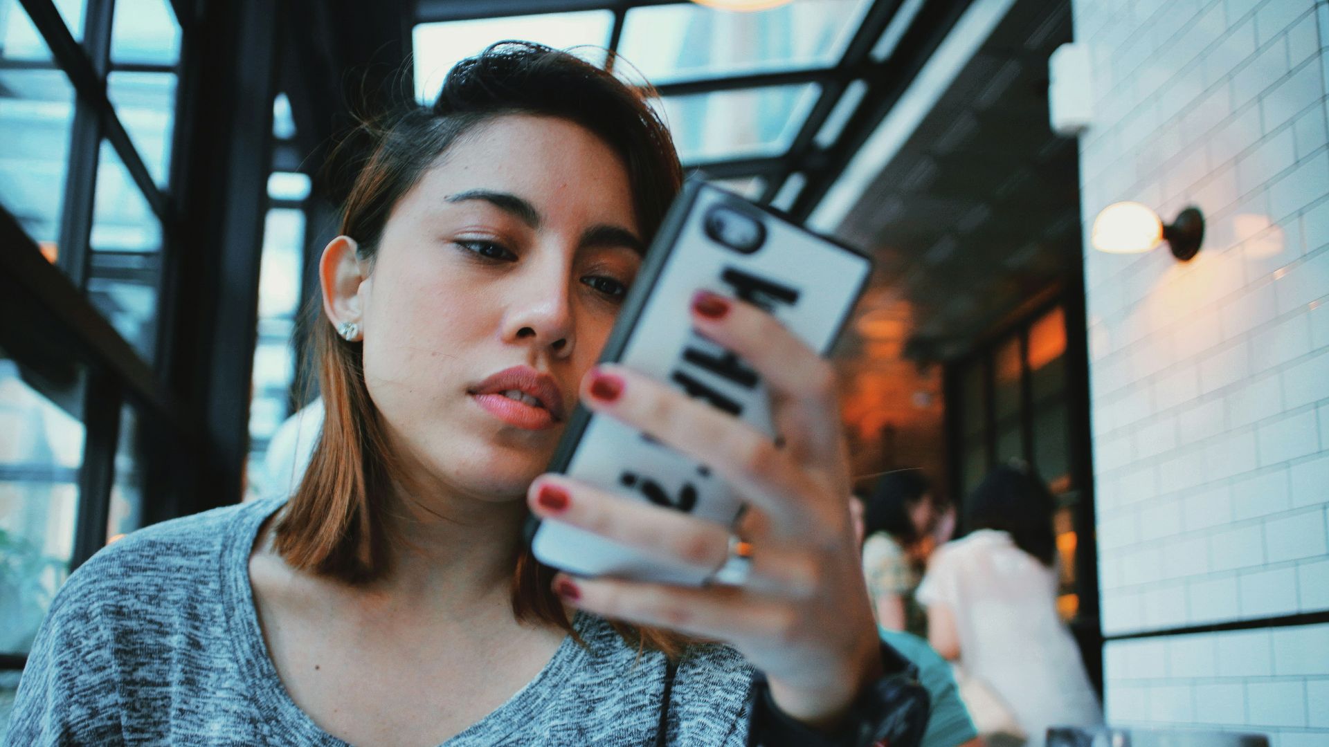 woman in gray and black sweater holding white and black iphone case