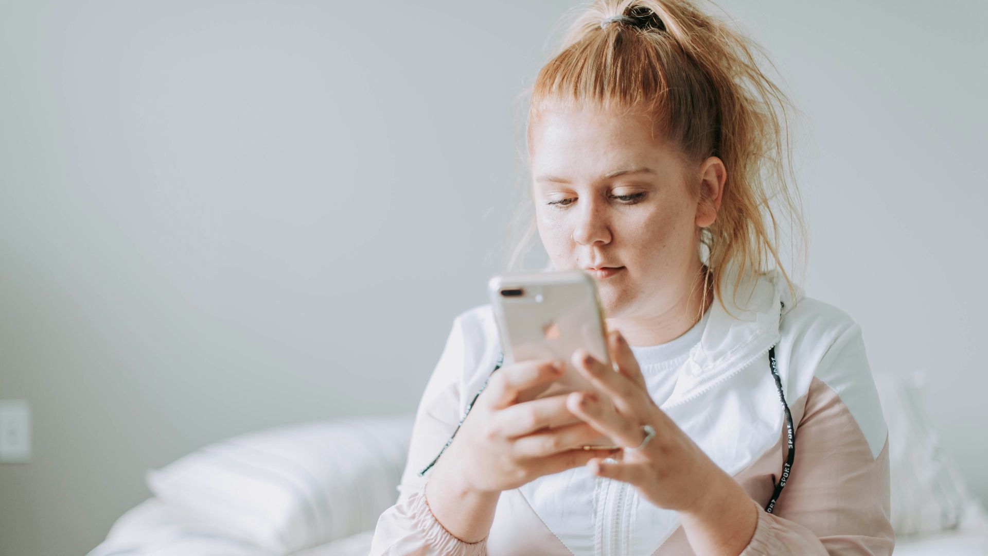 woman sitting on bed while using gold turned 8 Plus