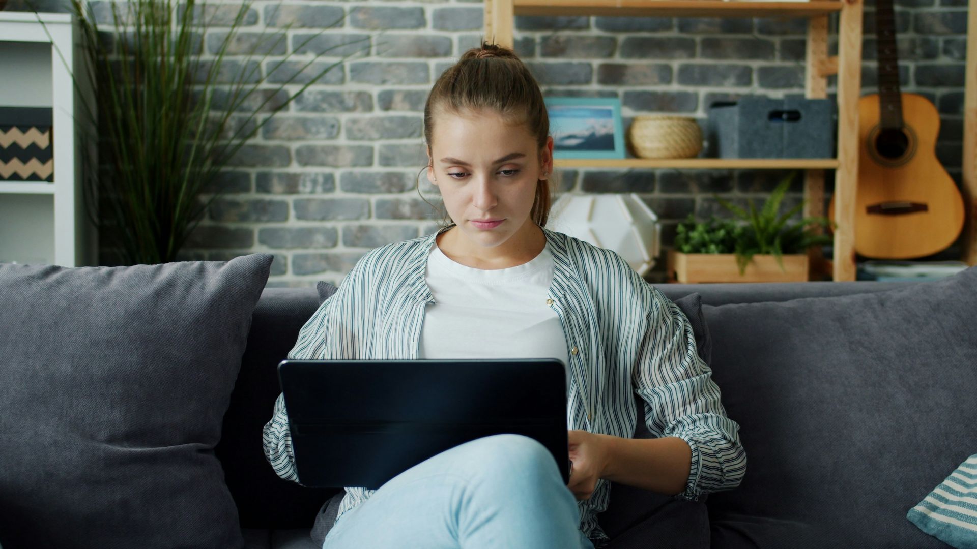 Young woman working on laptop on couch