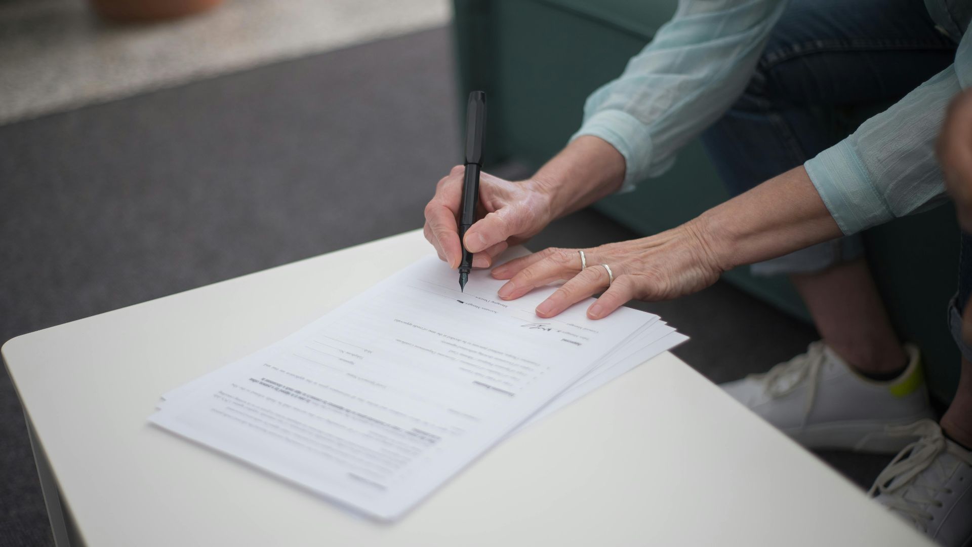 A person signing important legal documents on a table, emphasizing business and professionalism.