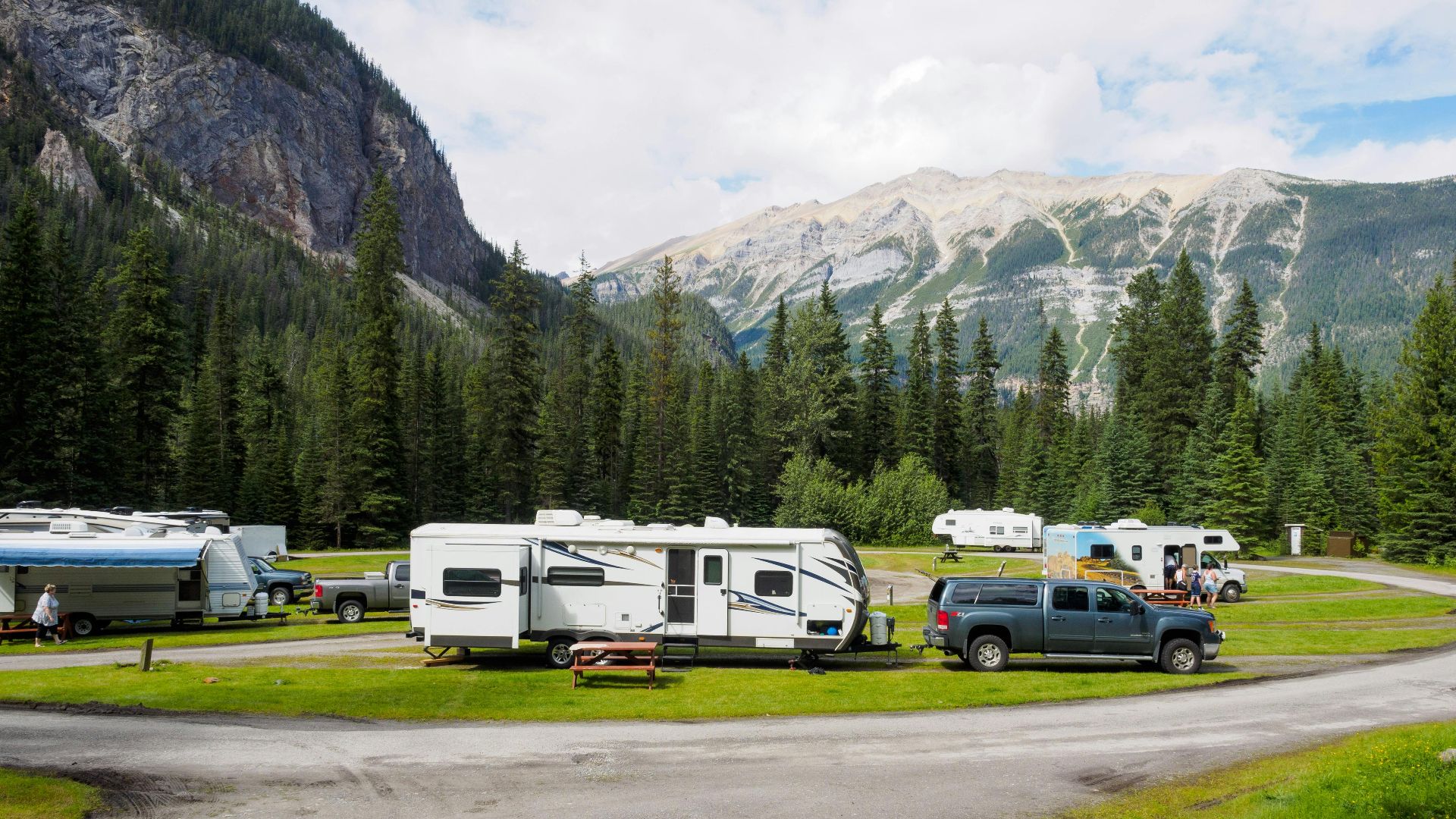 A beautiful campsite featuring RVs amidst lush forests and towering mountains for a peaceful getaway.