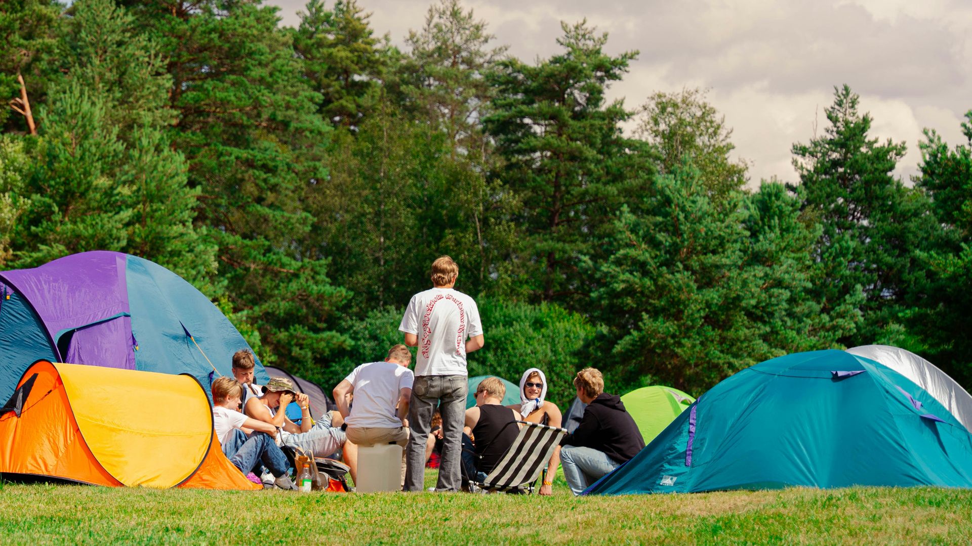 People are camping outside, gathered in a circle.
