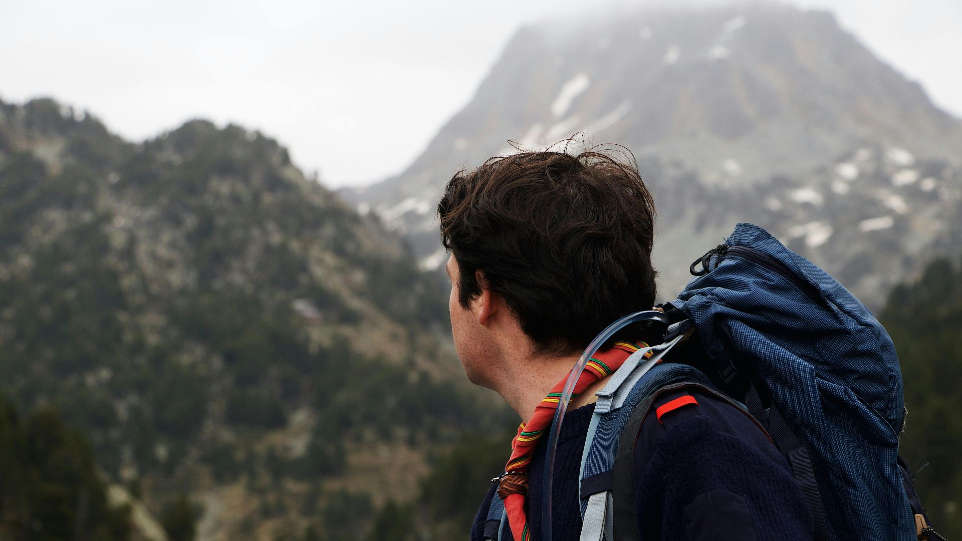 A man with a backpack hiking and enjoying mountainous scenery.