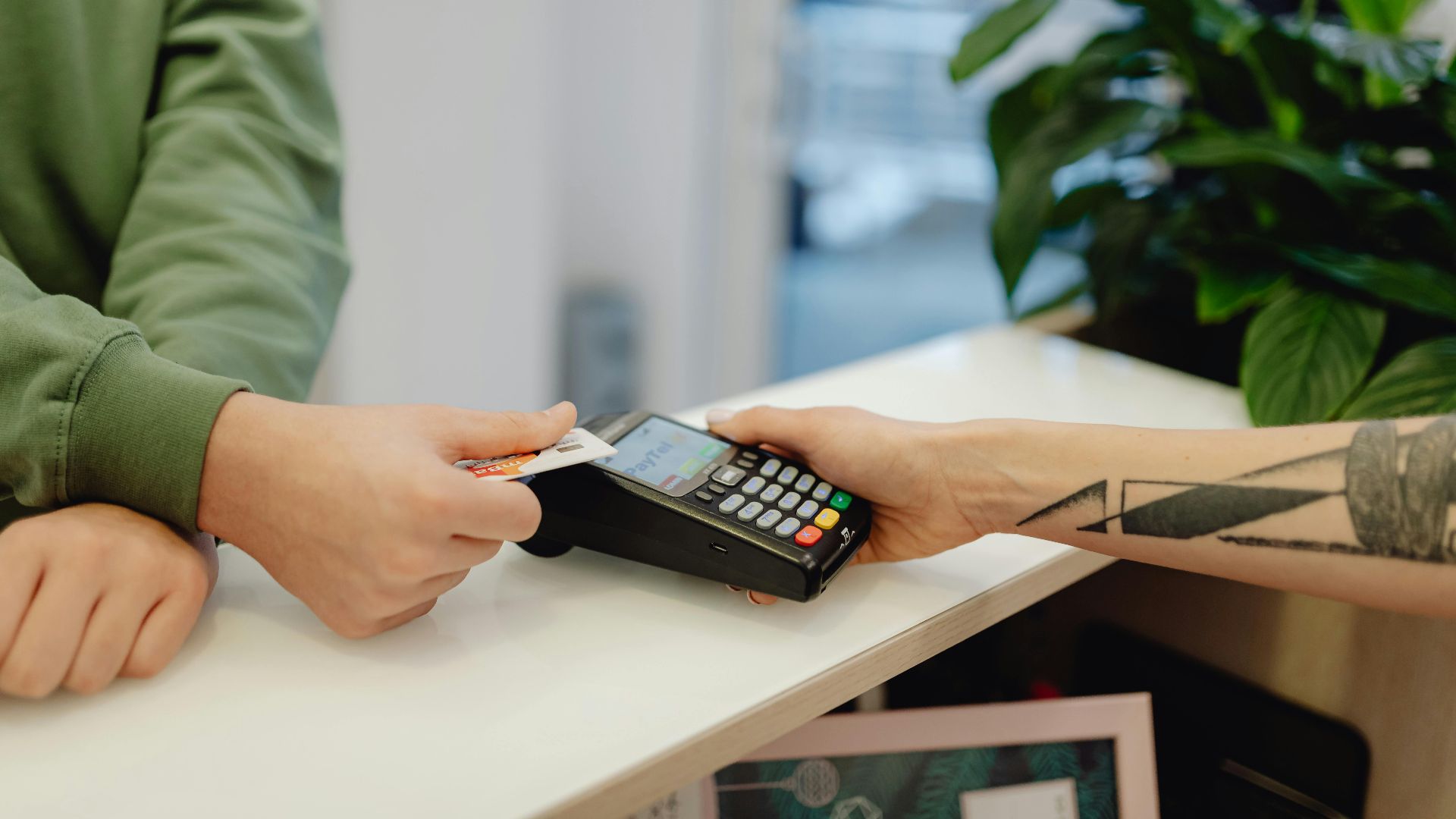A close-up view of a contactless payment being made with a bank card over a payment terminal.