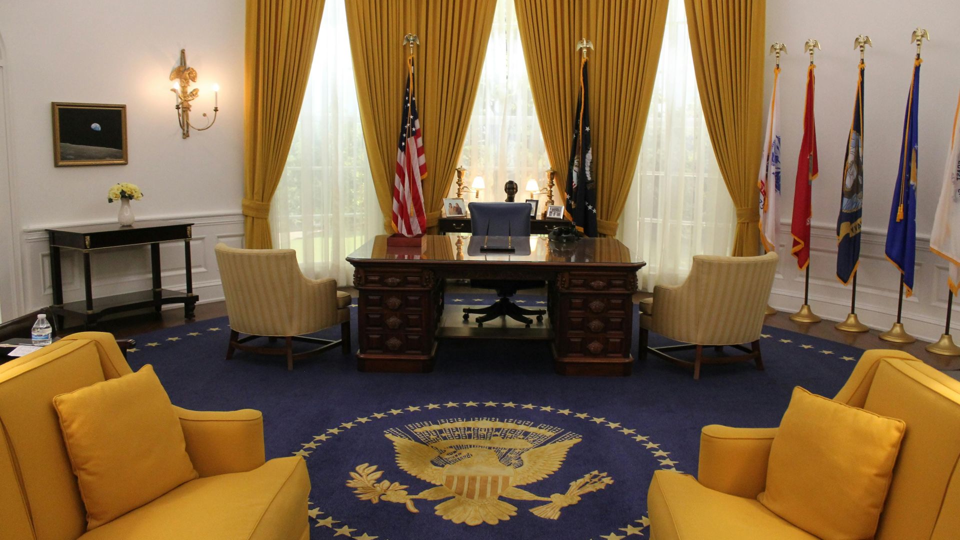 Interior of a presidential office showcasing elegant design with flags and majestic furnishings.