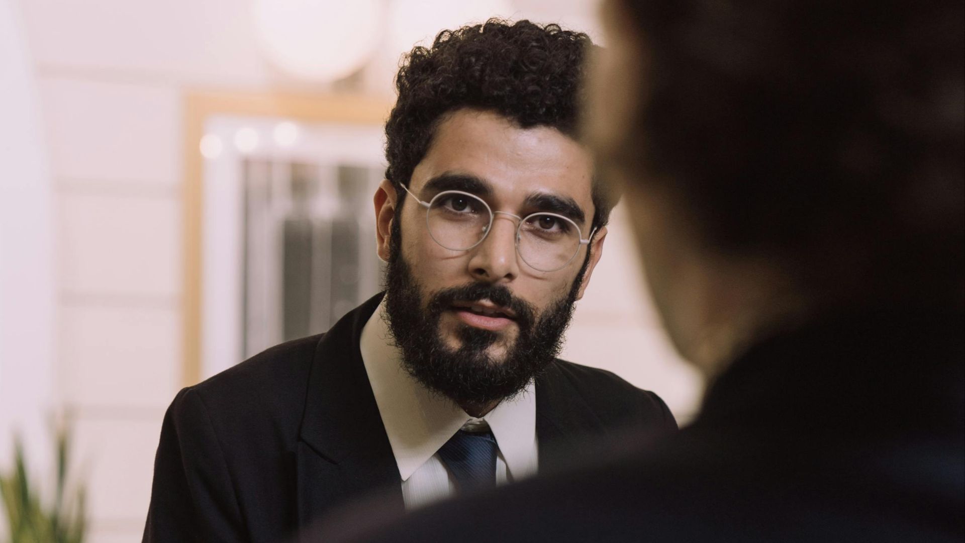 A professional businessman checks in at a hotel reception, engaging with a concierge.