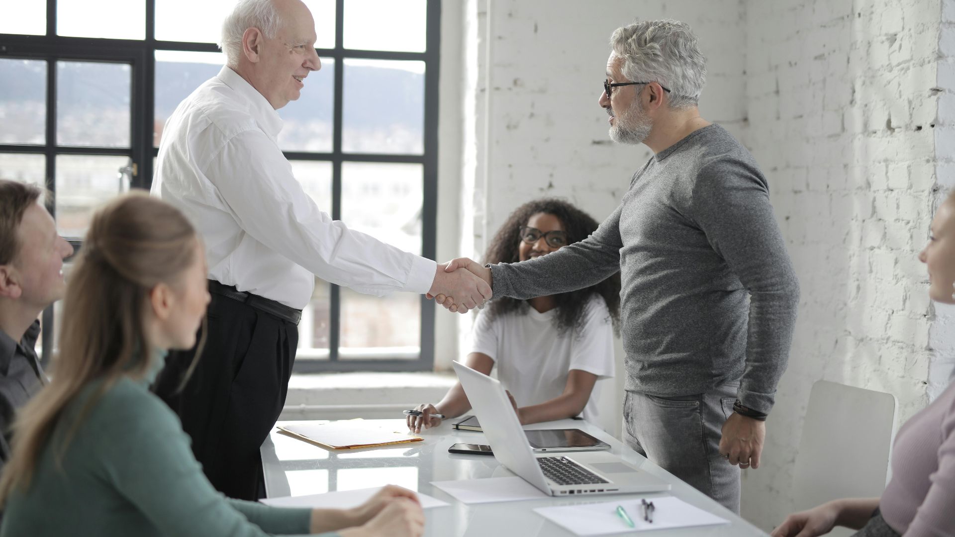 Business professionals shaking hands during an office meeting, symbolizing teamwork and cooperation.