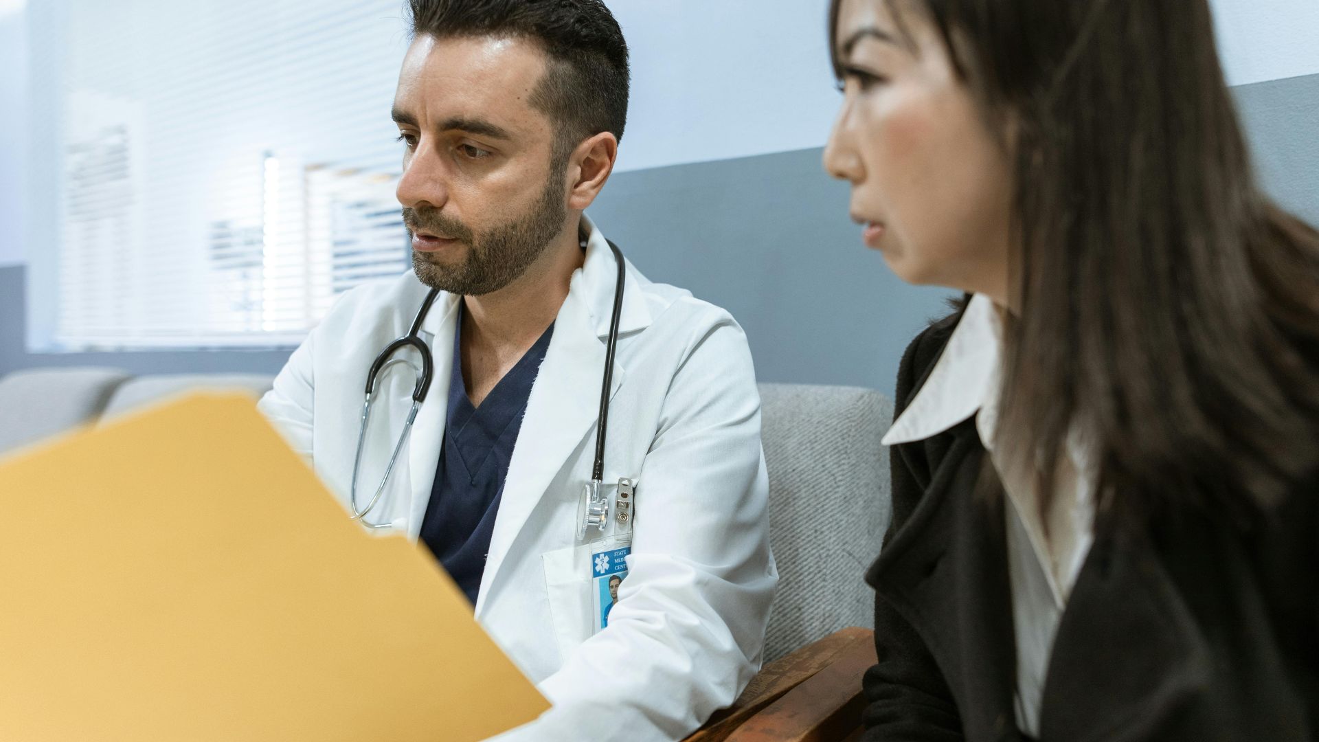 Doctor discusses health records with a patient in a clinical setting.