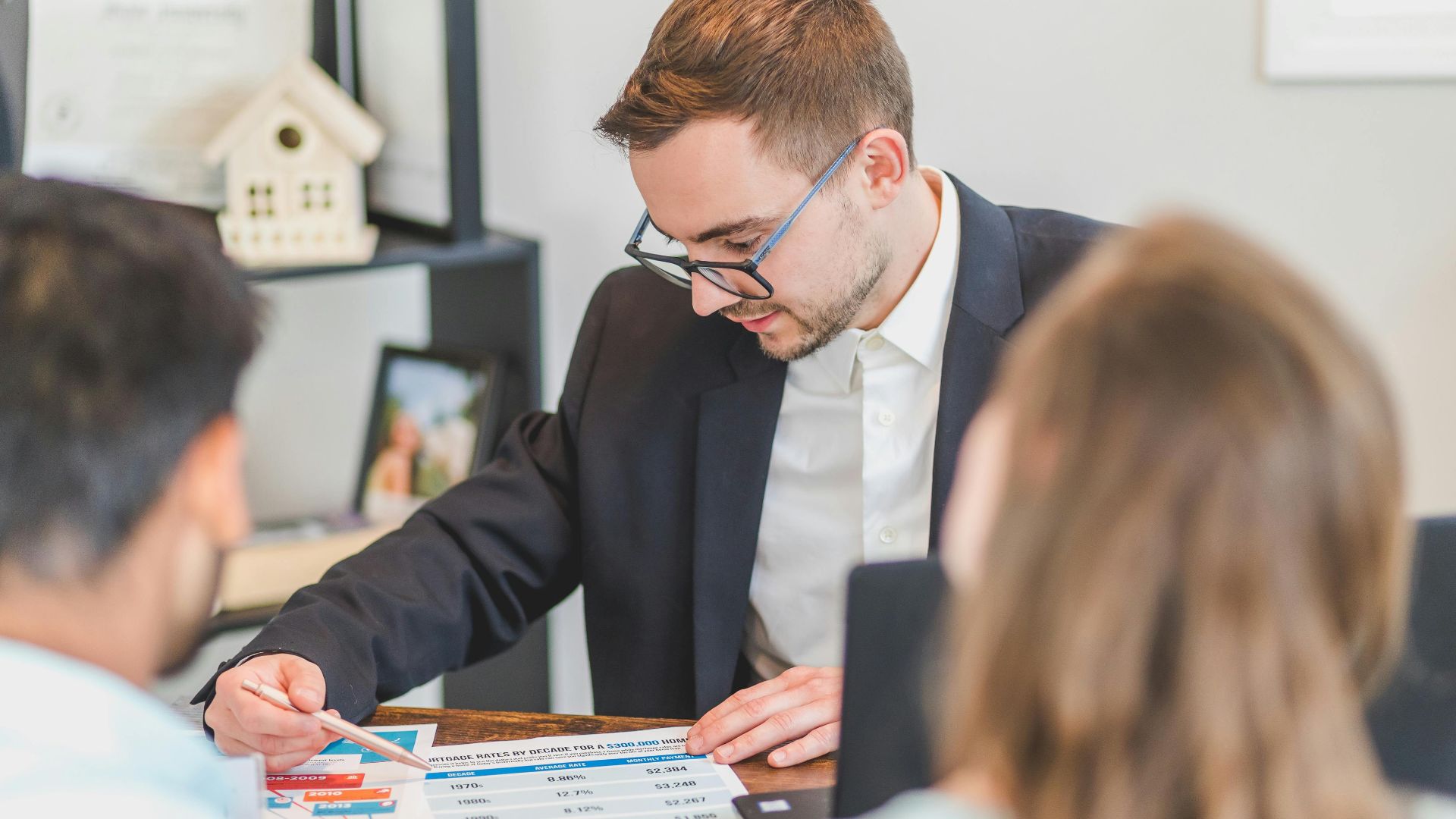 A real estate agent explains mortgage options to clients in an office setting.