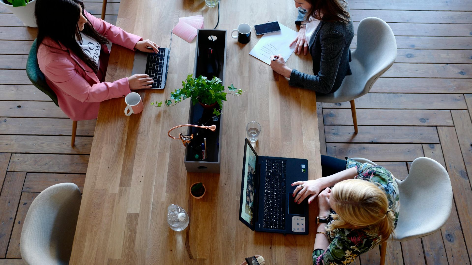 Overhead view of diverse women professionals working in a modern office setting, fostering collaboration and teamwork.