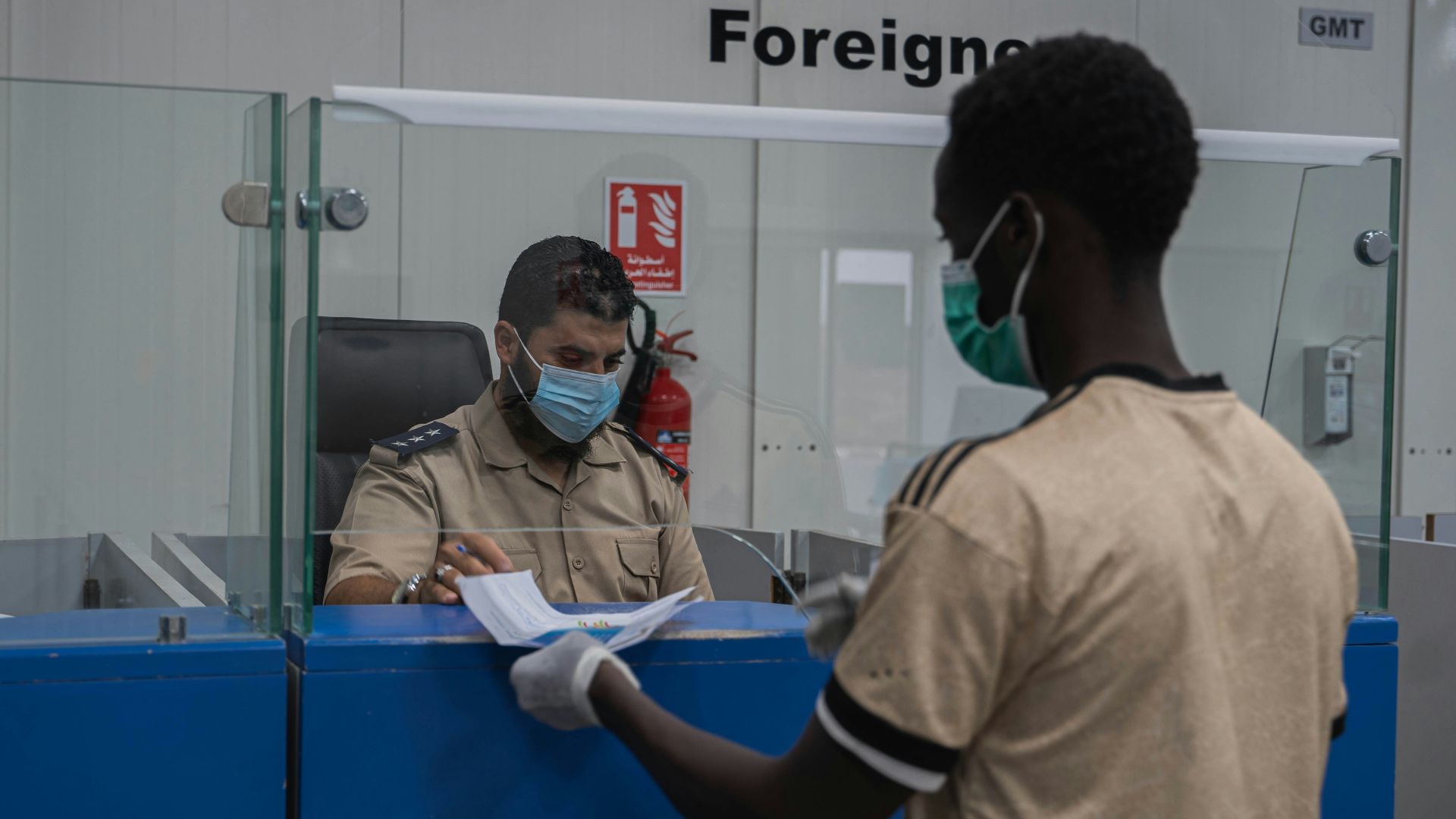 a man wearing a face mask and gloves standing in front of a counter