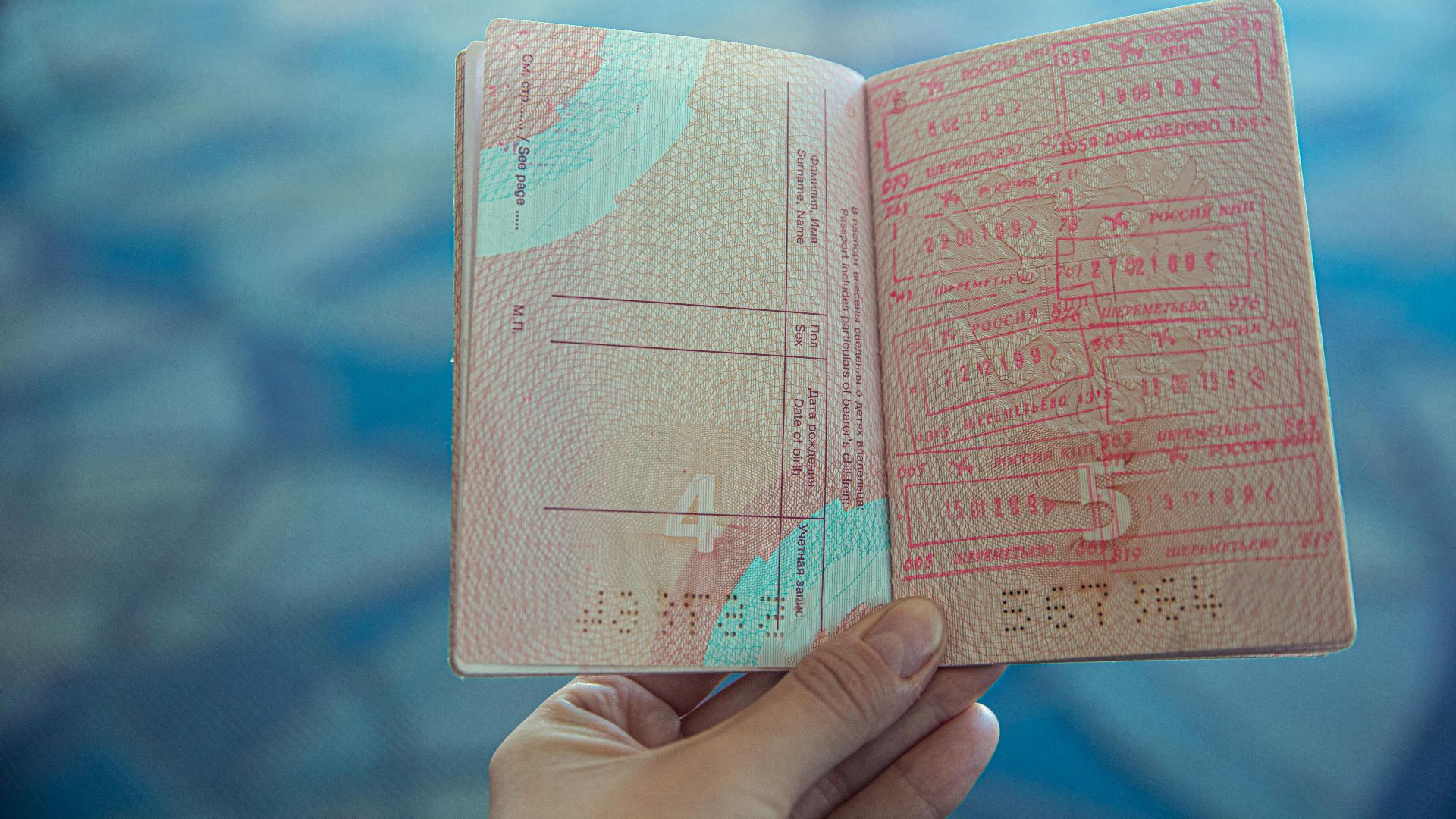 Close-up view of an open passport displaying various travel stamps in an airport setting.
