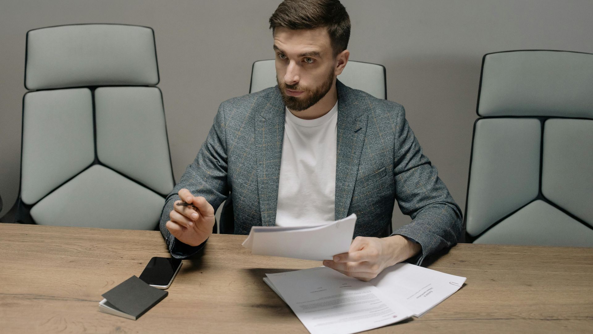 Professional businessman in a suit holding documents during a meeting in an office setting.