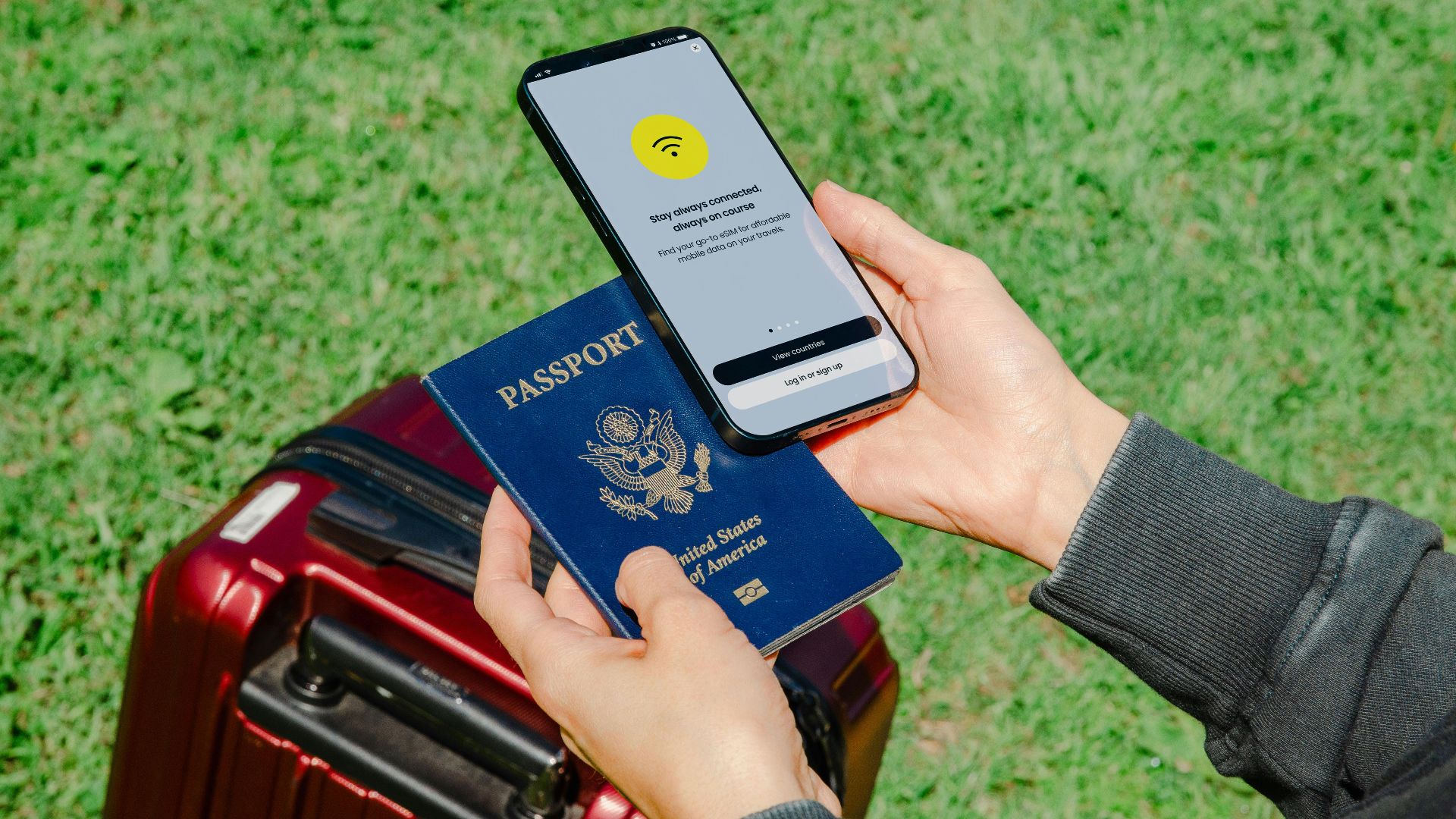 Close-up of hands holding a passport and smartphone with lost connection outdoors beside luggage.