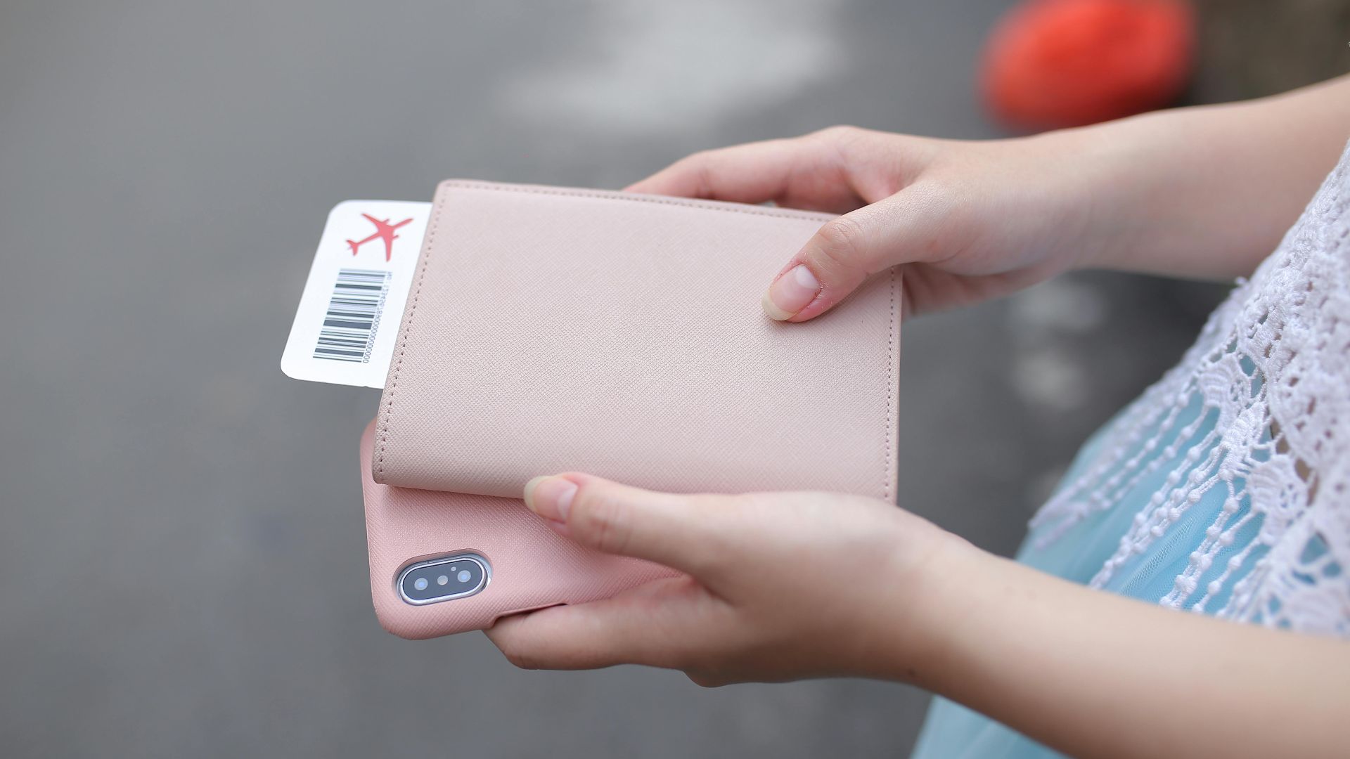 A woman holding a passport with a boarding pass and a smartphone, ready for travel.